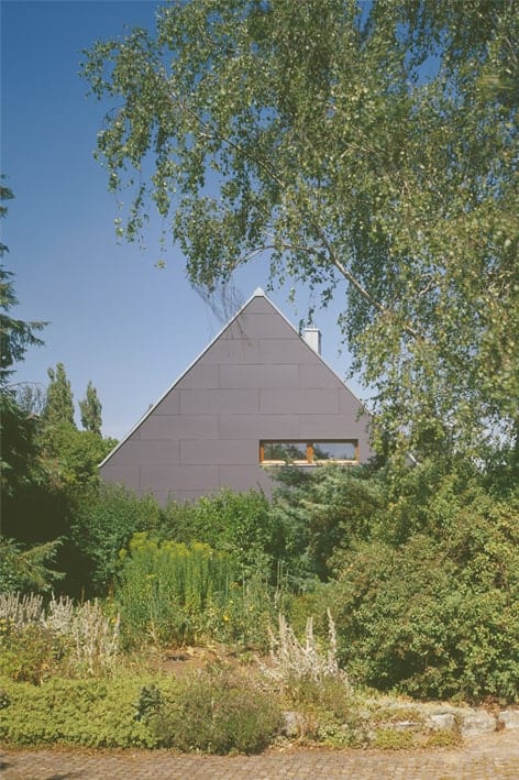 这是一个灰色色调的房子的外观，与周围的绿色树木景观相辅相成。