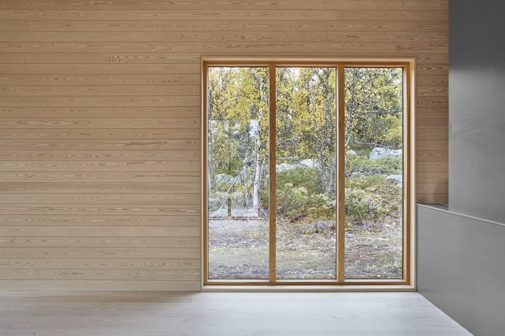 这是对房子内部的观察，它的墙壁和玻璃墙都采用了浅色的木质调。