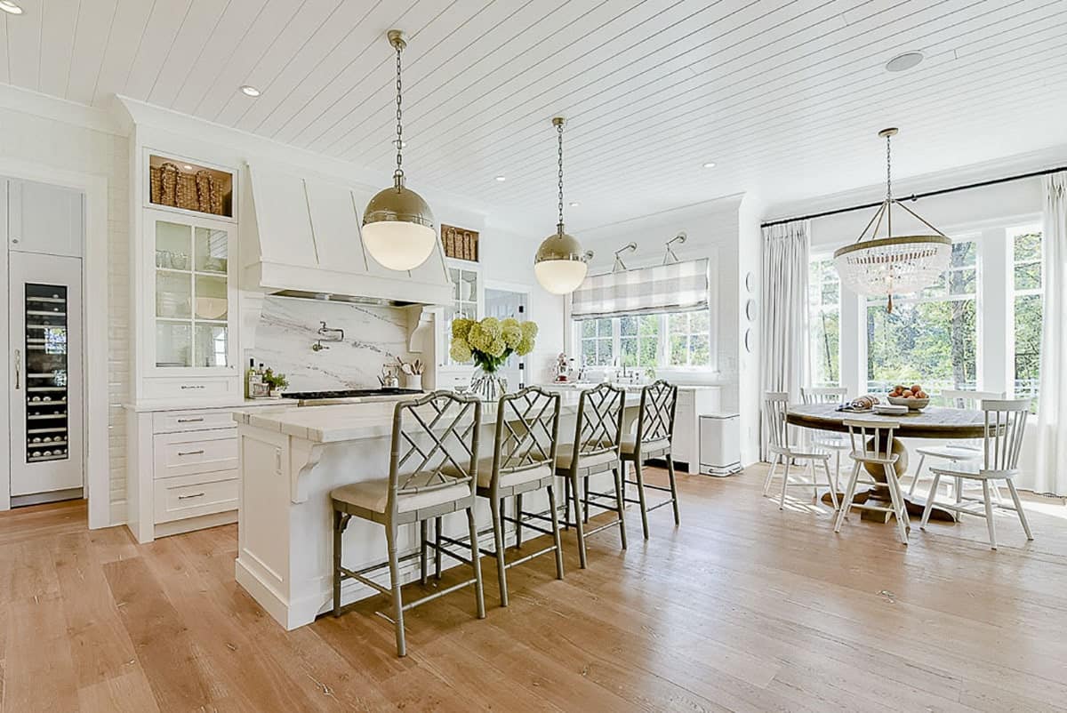 可用餐的厨房铺有浅色硬木地板和与白色橱柜相匹配的船形天花板。