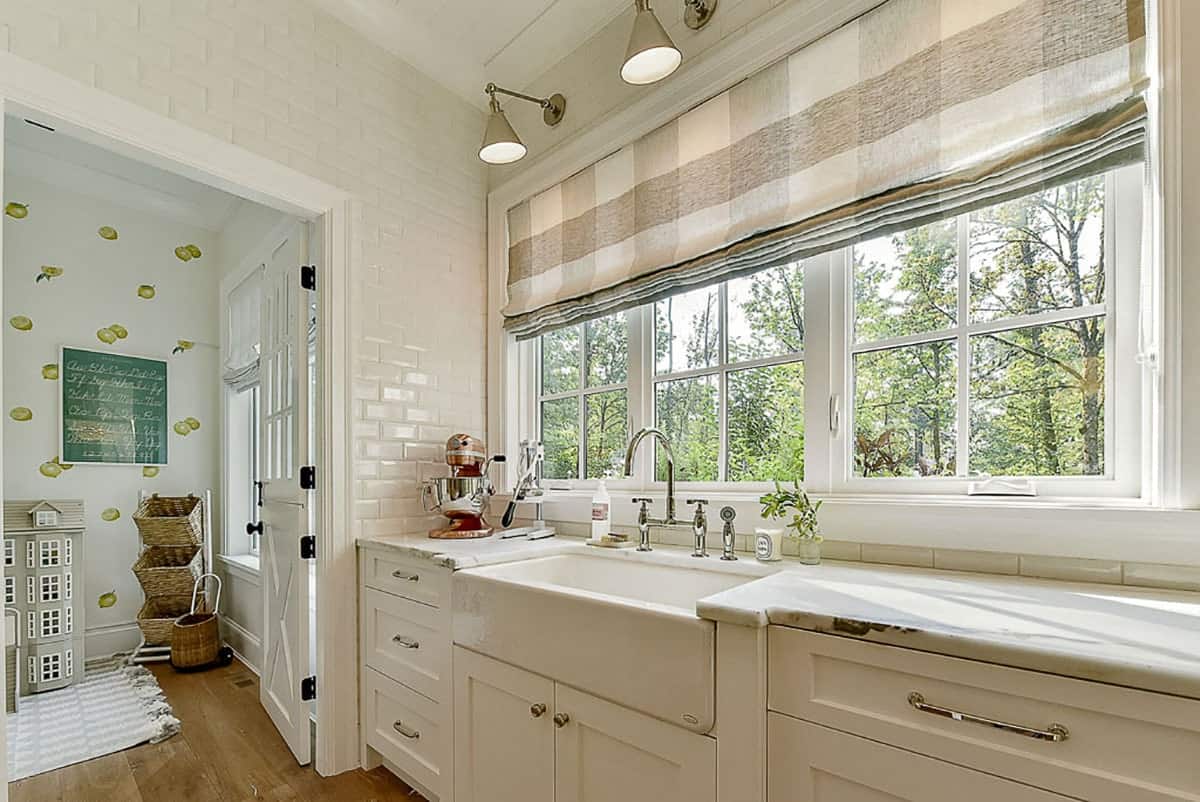 管家的食品室里有一个农家乐式的水槽、大理石台面和白色框窗，窗户上镶嵌着罗马方格窗帘。