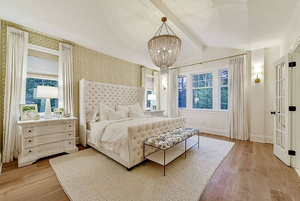主卧室有白色的家具，拱形的天花板，宽阔的木板地板，上面铺着黄麻地毯。