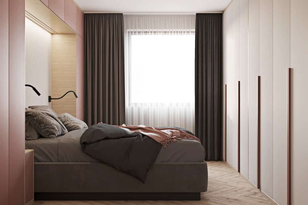 卧室通过远侧的窗户采光，暗灰色的窗帘与床单的色调相匹配。