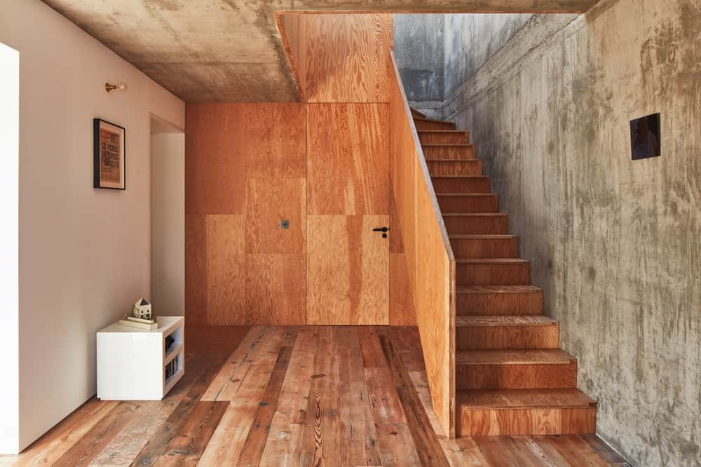 这是房子的木楼梯，与地板搭配得很好，辅以工业风格的灰色混凝土墙和天花板。