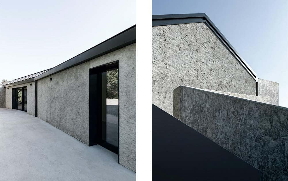 这是对房子混凝土外墙的双重观察，展示了玻璃墙、门和黑暗的屋顶。