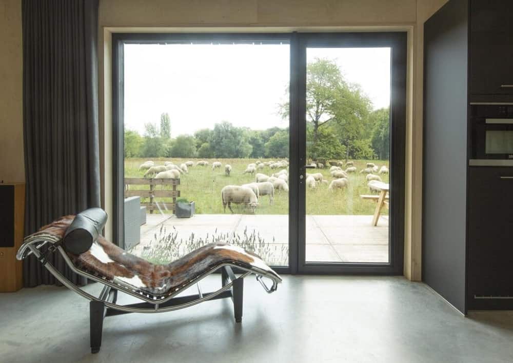 这是一扇玻璃门，通向房子后面的田野。它有一张躺椅，可以更好地欣赏风景和阳光。