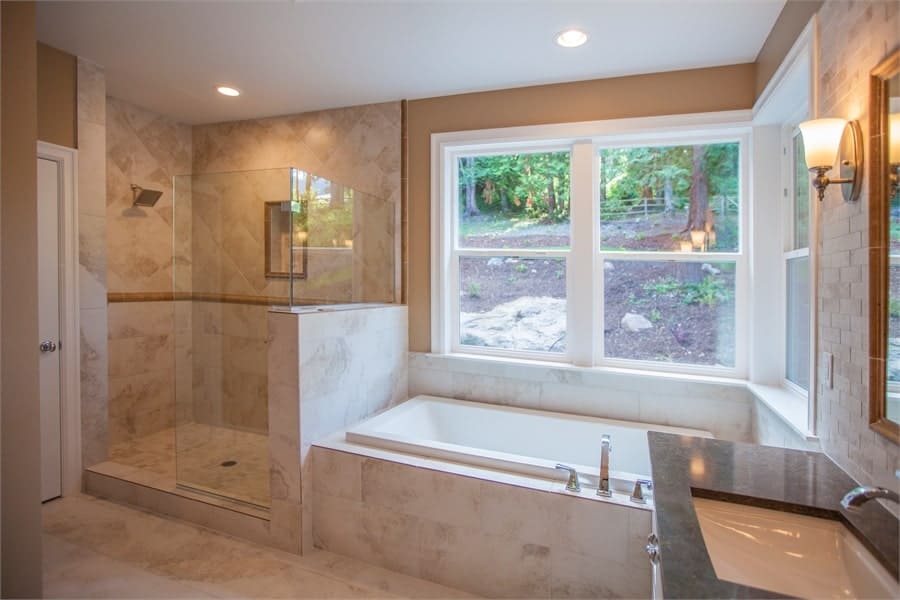 主浴室设有步入式淋浴间和落地式浴缸，放置在观景窗下。