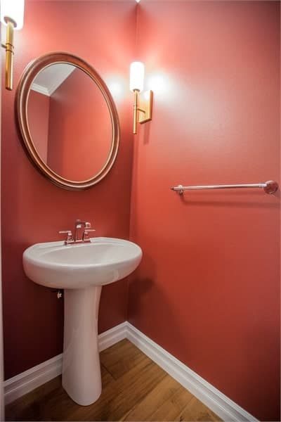 盥洗室里有一个洗手台，一面圆形镜子靠在红色的墙上。