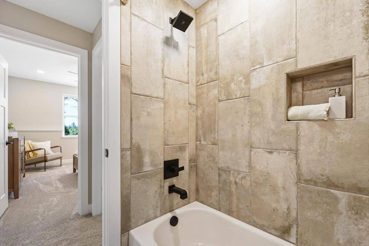 淋浴和浴缸组合，瓷砖墙，锻铁装置，和一个嵌入的架子。