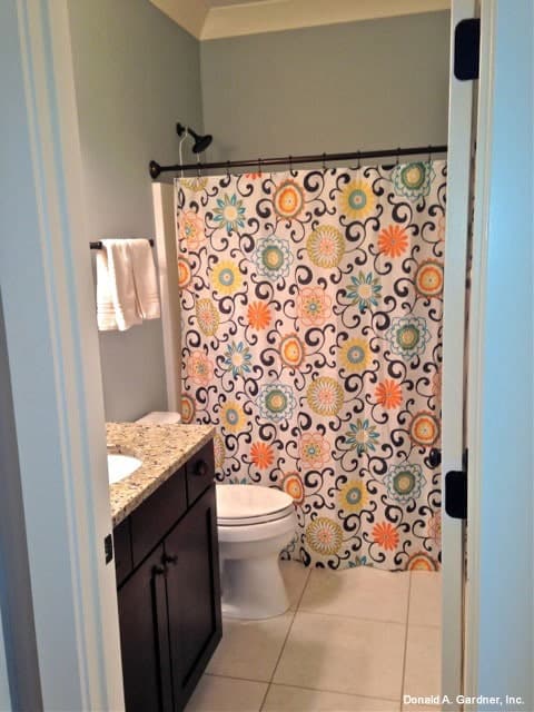 浴室里有一个洗手池、一个梳妆台、一个马桶和一个用花窗帘围起来的淋浴区。