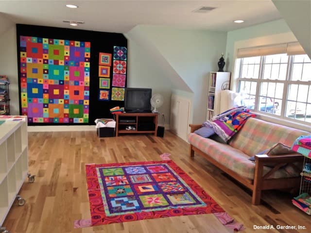 有格子沙发、彩色地毯和放在木柜上的电视的奖励房间。