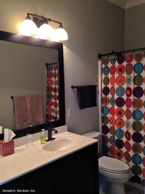 浴室配有深色木质梳妆台、卫生间和隐藏在彩色波点窗帘中的淋浴区。