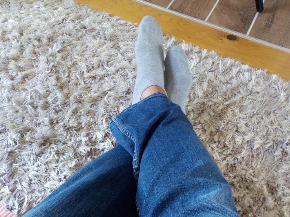 一个男人穿着袜子的脚在粗毛地毯上。