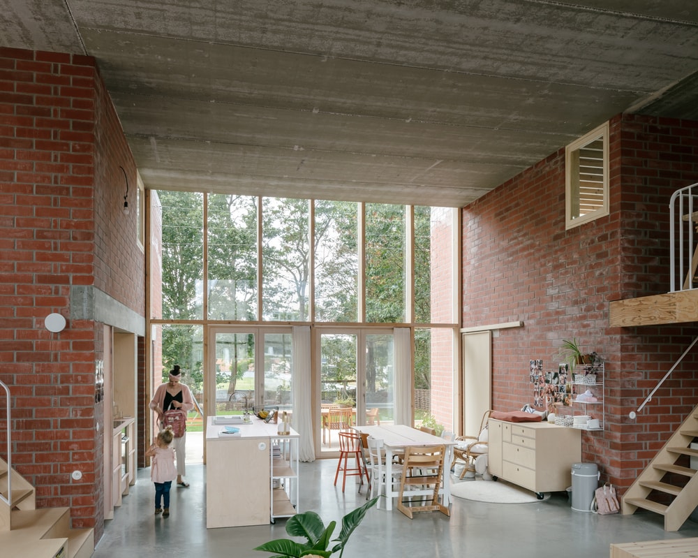 厨房和用餐区相邻，两侧是高大的红砖墙，与家具的浅色色调形成对比。