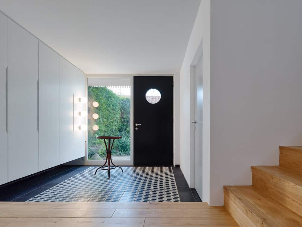 一进入房子，你就会受到这个简单的门厅的欢迎，它有一个深色的正门，与地板的色调相匹配。靠窗的是放展品的木桌。