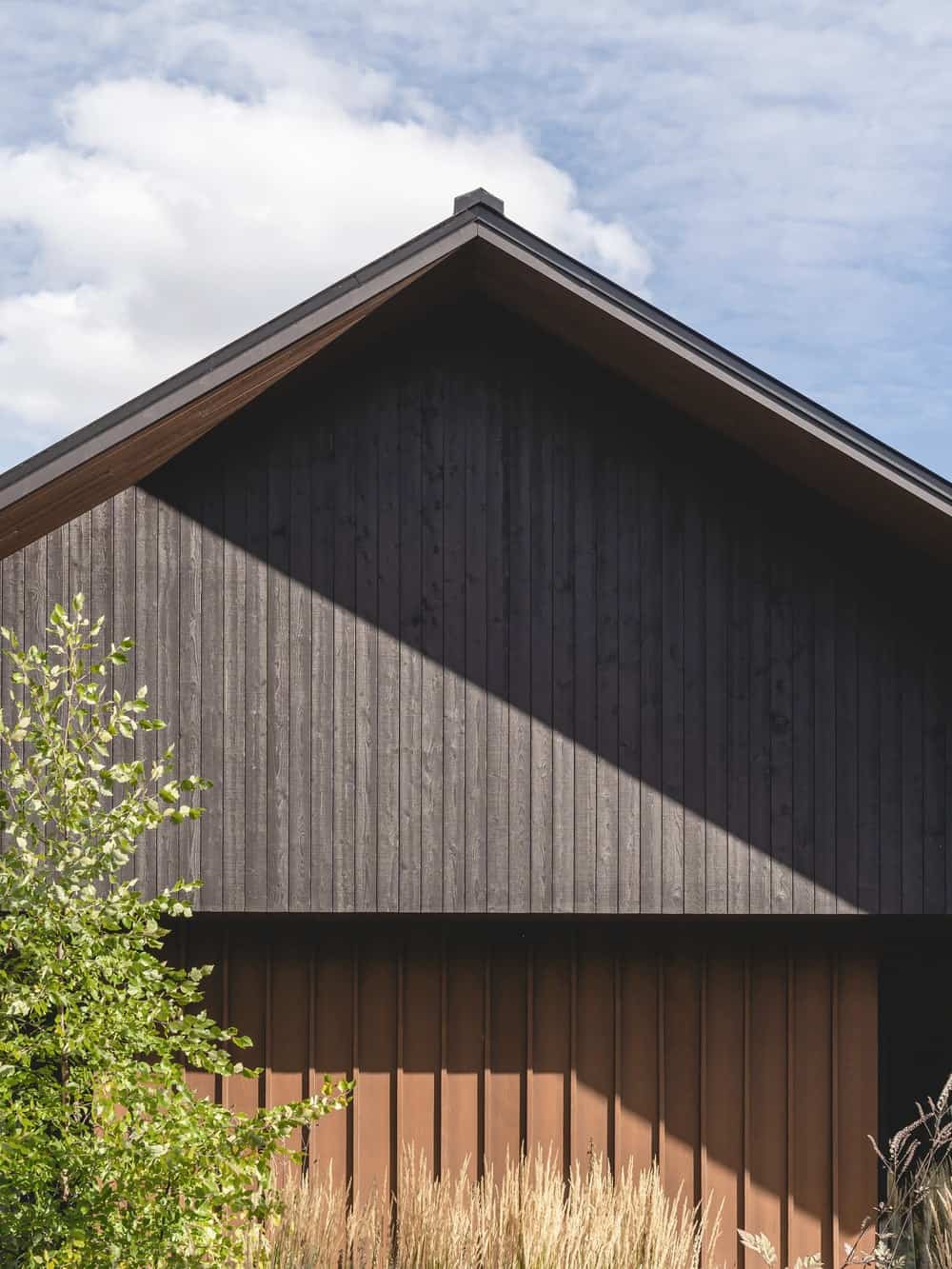 这是房子的深色木质外墙和a型框架屋顶的近距离观察。