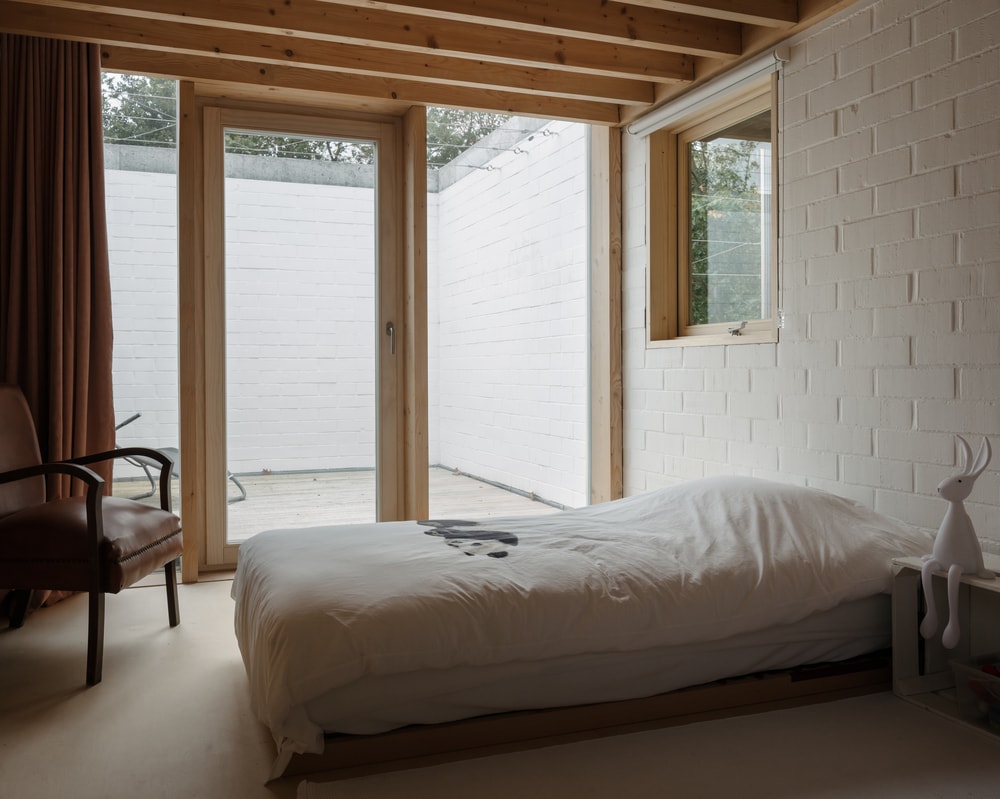 这是一间卧室，里面有一张低矮的木制台床，远处有一面玻璃墙，通往一个露台。