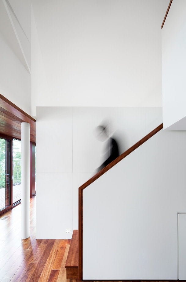 这是楼梯的侧视图，木扶手与硬木地板相匹配，与白墙形成对比。