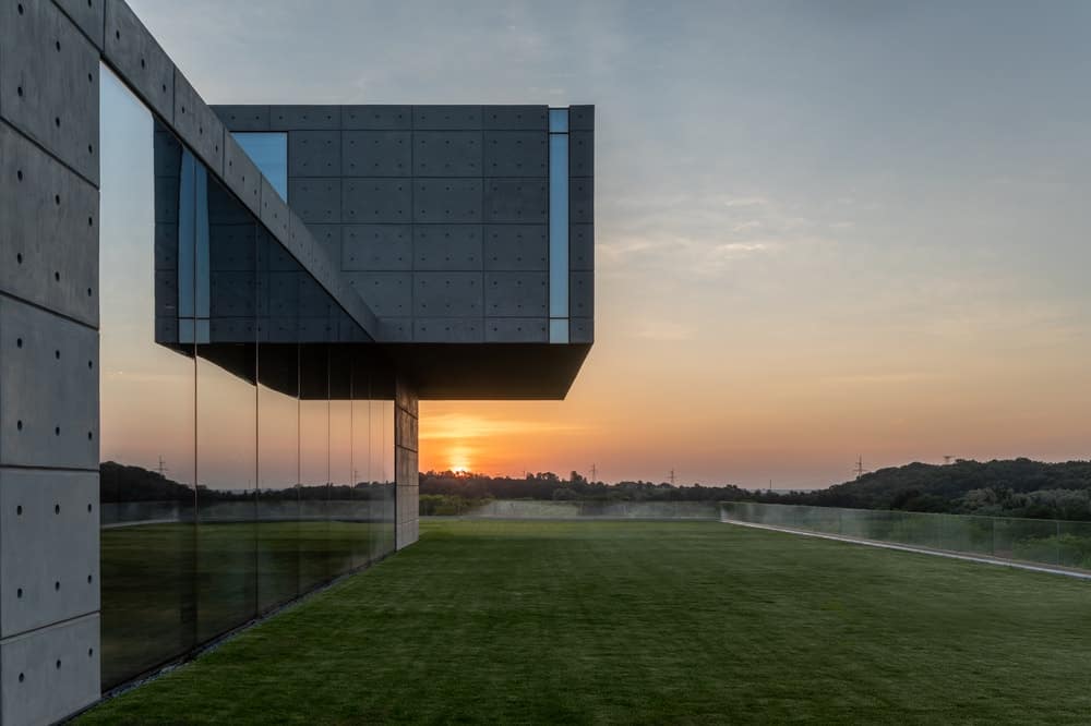 这是一栋拥有现代结构和玻璃墙的房子的日落景观。