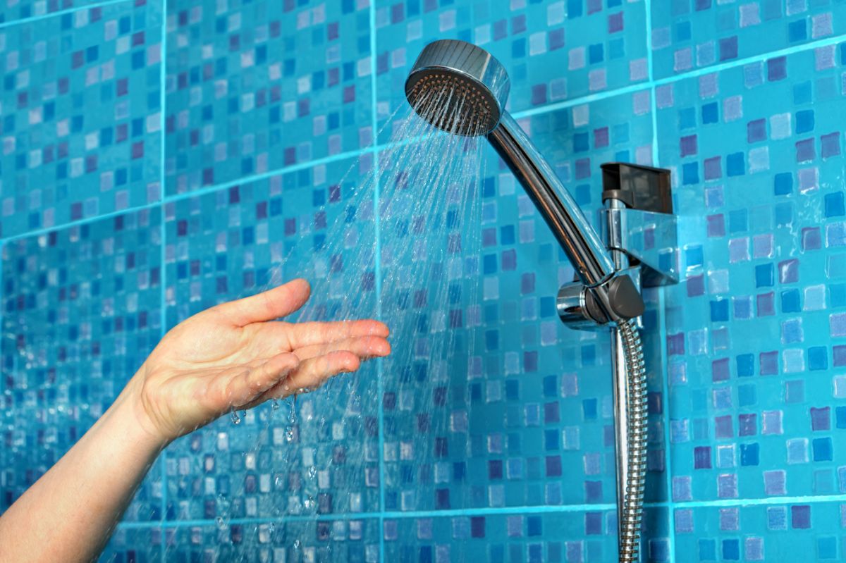 一个女人在滑杆式淋浴喷头上试水。