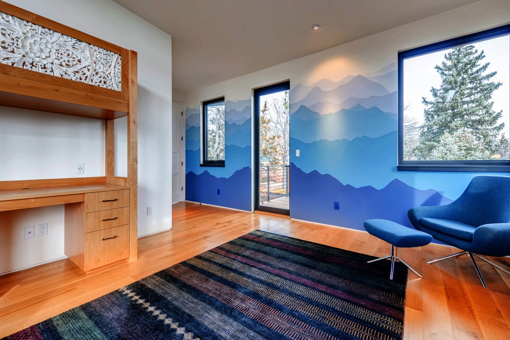 这间家庭办公室有彩色的墙壁、自然采光和一张带嵌入式橱柜和抽屉的大木桌。
