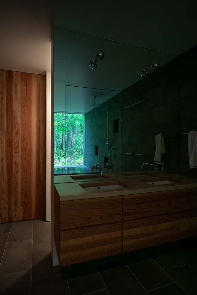 这是一个近距离观察现代两个洗手台的浴室，上面有一面大镜子墙。