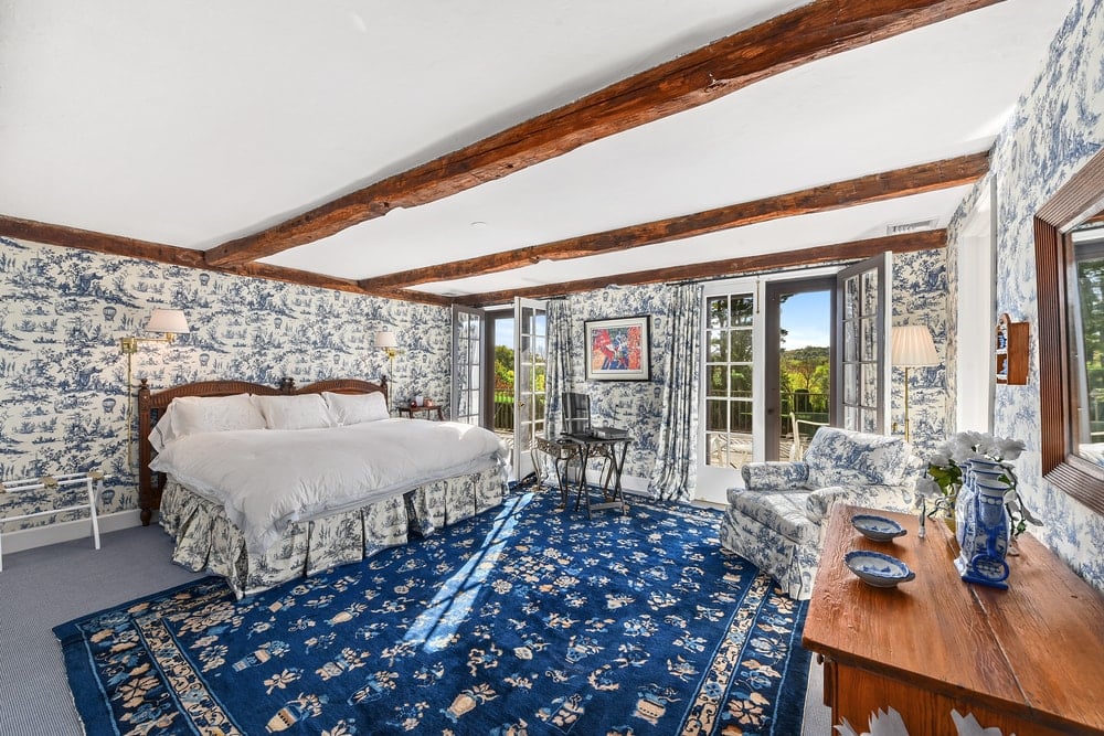 这张床的墙上有图案，床脚的蓝色图案地毯被法式玻璃门的自然光照亮。图片来自Toptenrealestatedeals.com。
