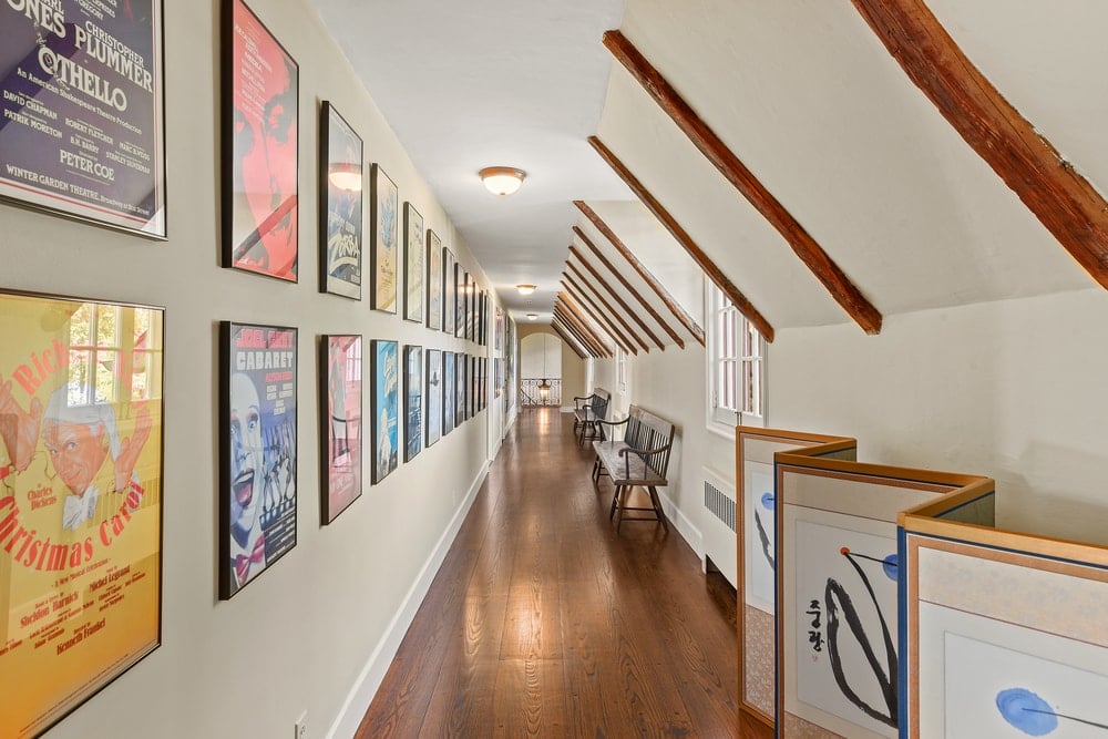 这是房子里的一条走廊，有一面长墙，墙上挂满了彩色的艺术品，对面有一张长凳可以观赏。图片来自Toptenrealestatedeals.com。