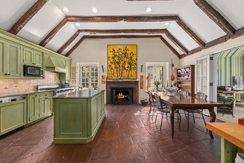 厨房有一个凹形天花板，外露的木横梁与硬木地板相匹配，与绿色的厨房岛台和橱柜形成对比。图片来自Toptenrealestatedeals.com。