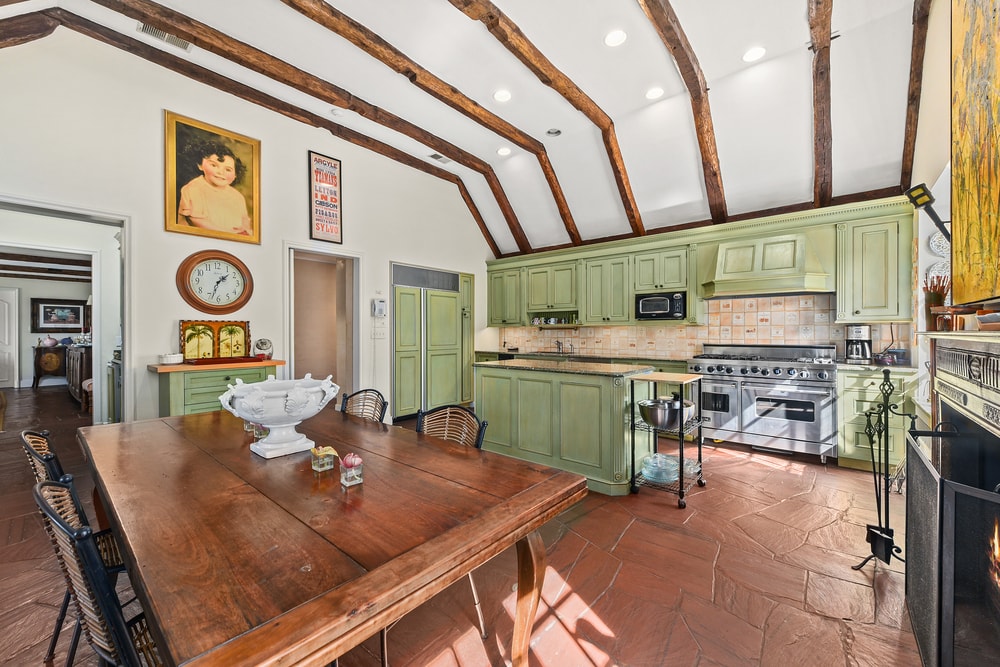 厨房的另一个视角展示了更多的绿色结构和厨房的橱柜，在深色硬木地板的衬托下脱颖而出，与木制餐桌相匹配。图片来自Toptenrealestatedeals.com。