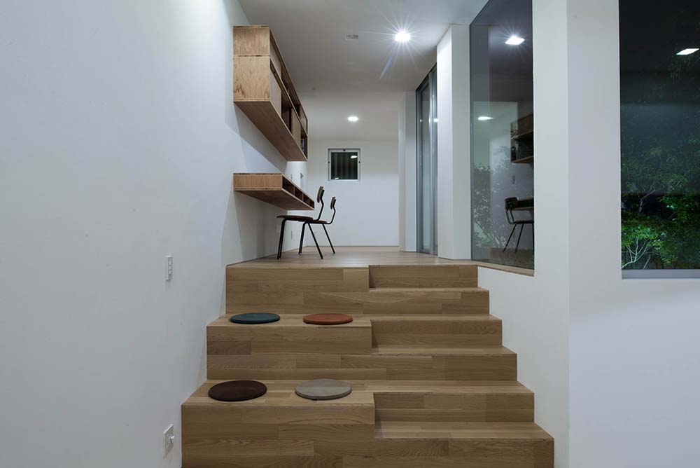 这是一个家庭办公室，有一个高架区域，内置的浮动桌子，架子和一组木台阶。