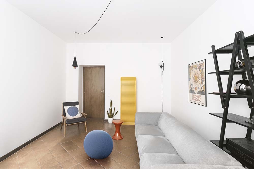 这是一个大客厅，里面有一个大灰色沙发，搭配着彩色的结构，与明亮的墙壁形成对比。