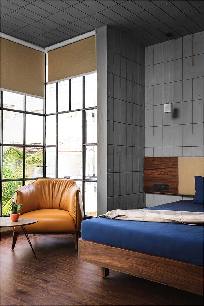这是一间卧室，有一个木制的平台床架，与硬木地板相匹配，被一侧休息区的玻璃墙照亮。