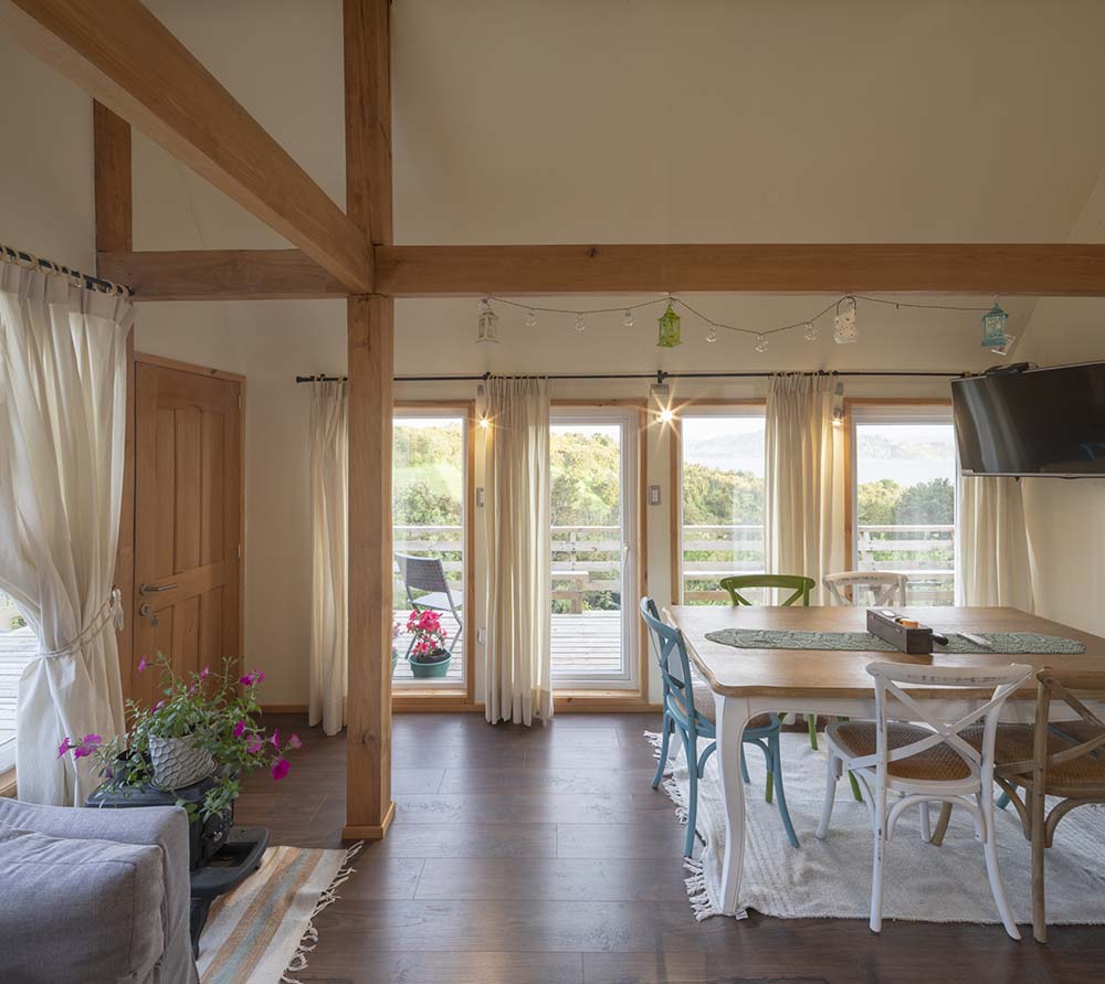 房子的用餐区有一个长方形的餐桌，与硬木地板相匹配，与白色交叉背椅形成对比。
