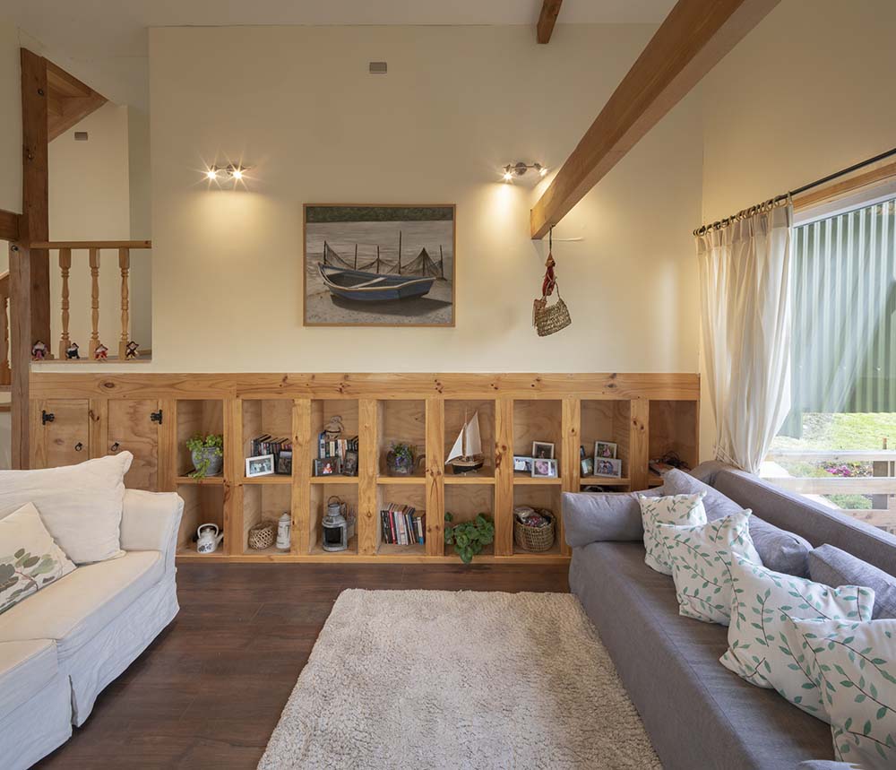 客厅里有几张沙发，背景是木架子、壁挂式艺术品和木天花板横梁。