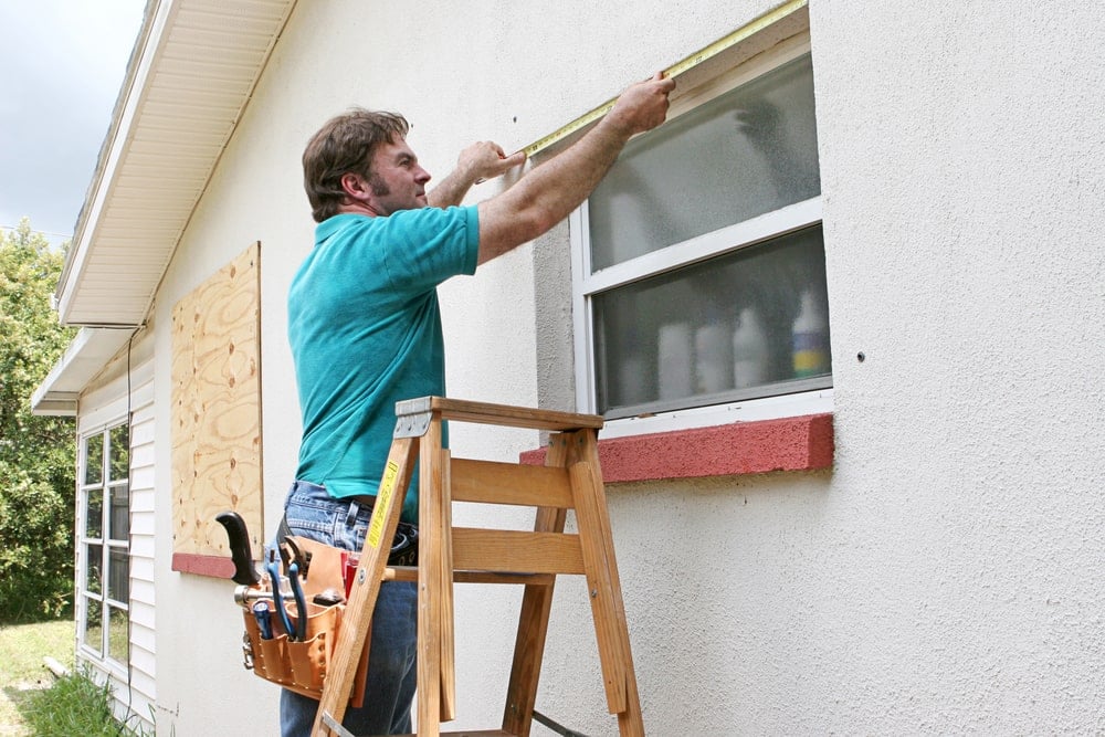 一名男子正在测量安装防风窗的窗户。