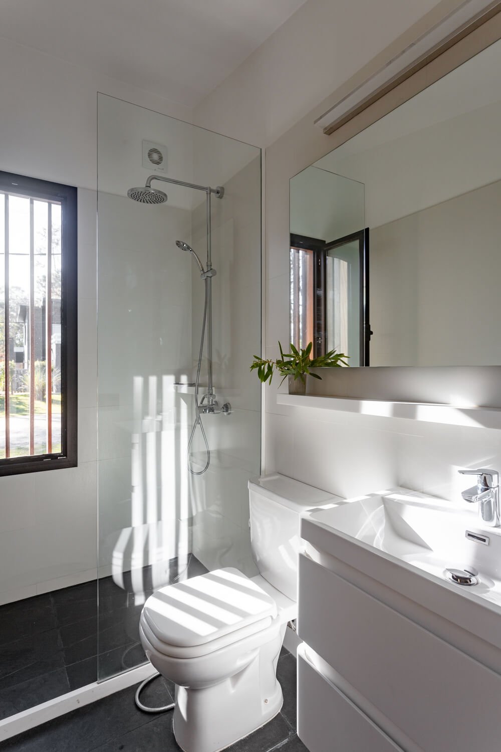 浴室的淋浴区、梳妆台和卫生间都采用了一致的亮白色调，自然光线使其更加明亮。