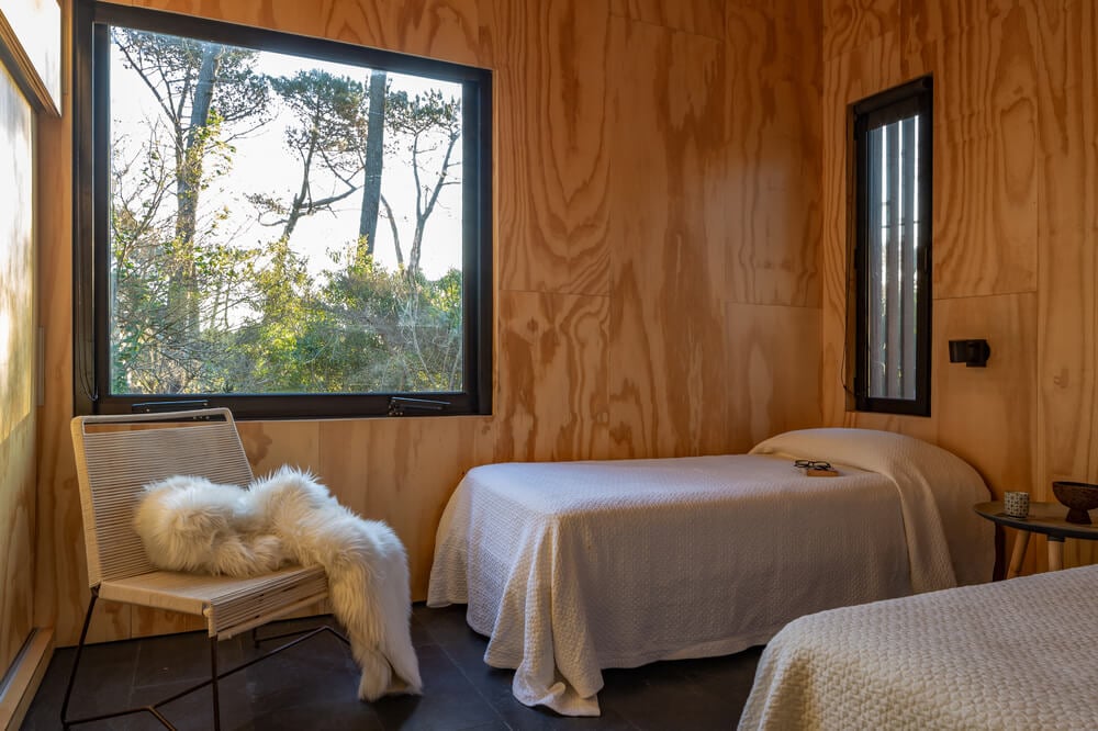 另一间卧室里有两张小床和多扇窗户，让木墙和天花板更加明亮。
