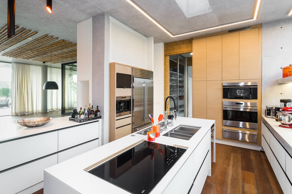 白色的现代橱柜和厨房岛台由不锈钢和黑色元素的电器补充。