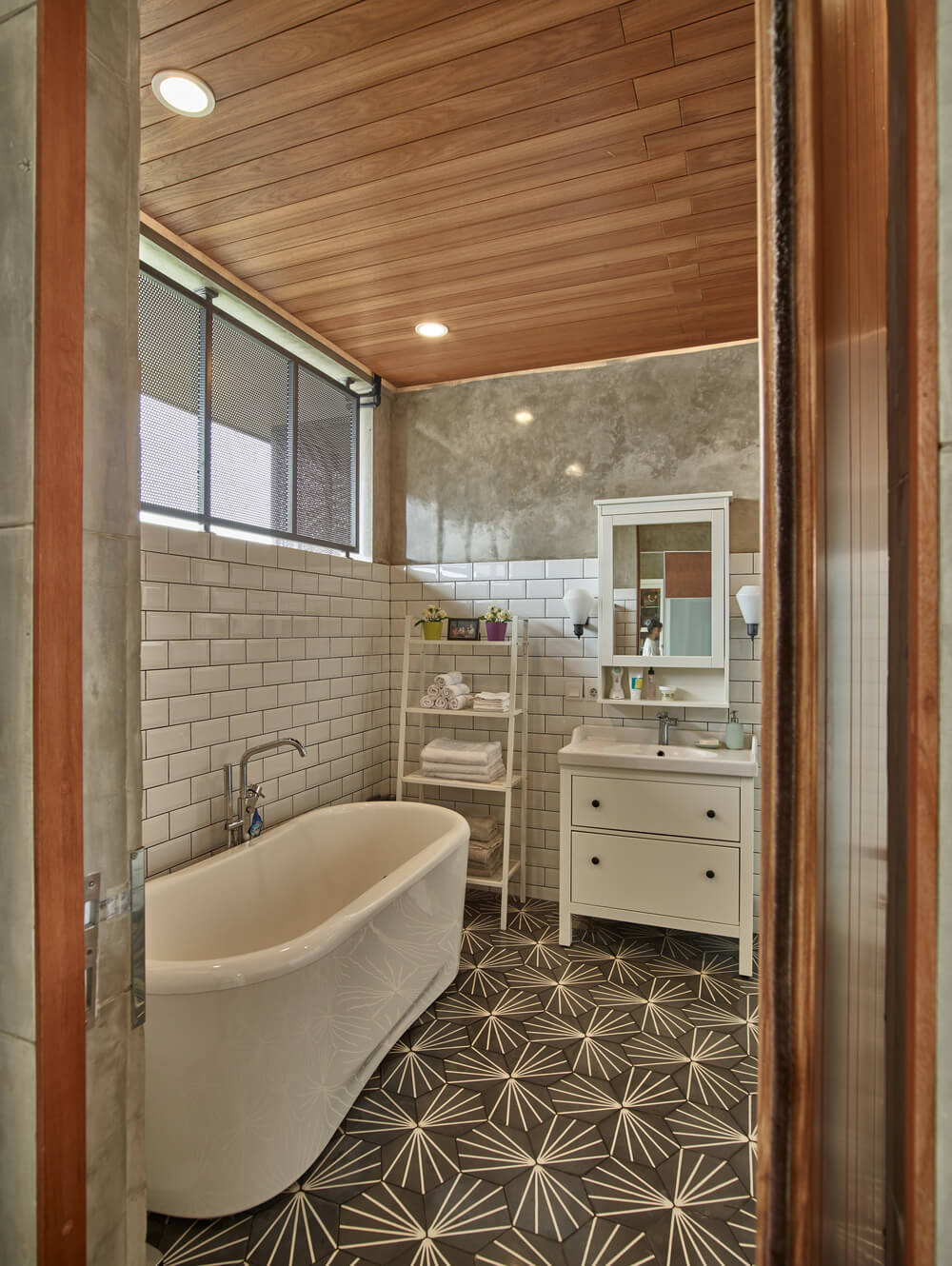 另一间浴室的窗户下有一个独立的大浴缸，墙上贴着白色的地铁瓷砖。