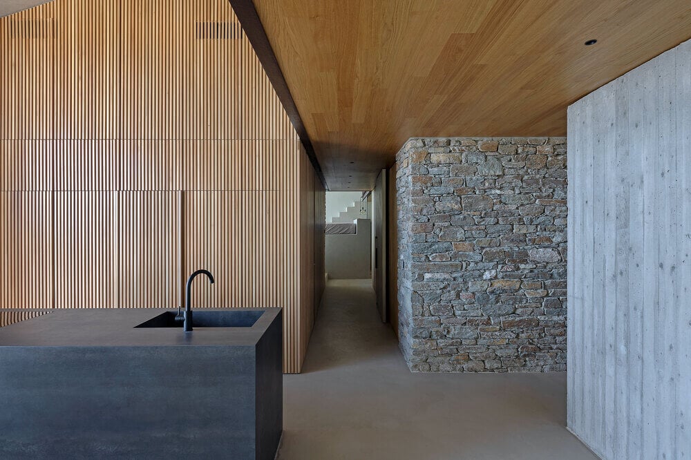 厨房岛台的远角有一个水槽，厨房一侧是一条有土坯墙的走廊。