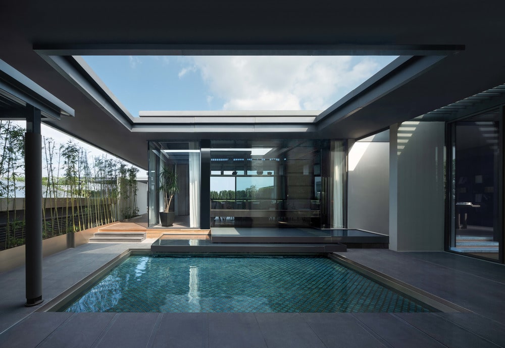 游泳池的另一个视图显示了远处房子的玻璃墙以及木制甲板走道。