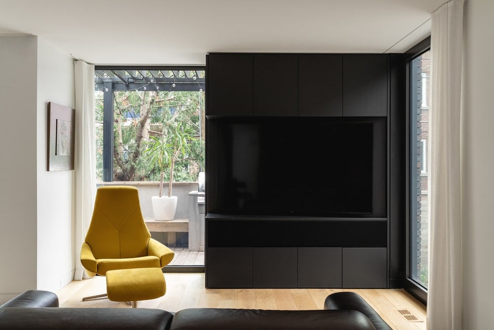 客厅里有一个黑色的大电视架的黑色皮革沙发对面,与实木地板。