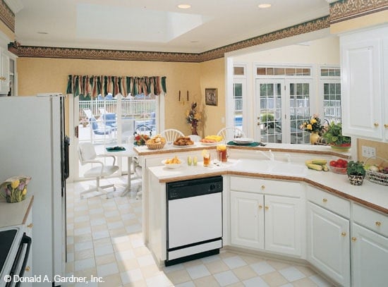 厨房配备了白色电器、花岗岩台面、凸起的半岛和黄铜五金强调的白色橱柜。