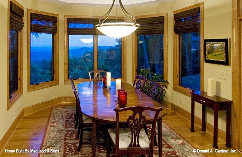 带凸窗的用餐区和椭圆形的用餐组坐在有边框的区域地毯上。