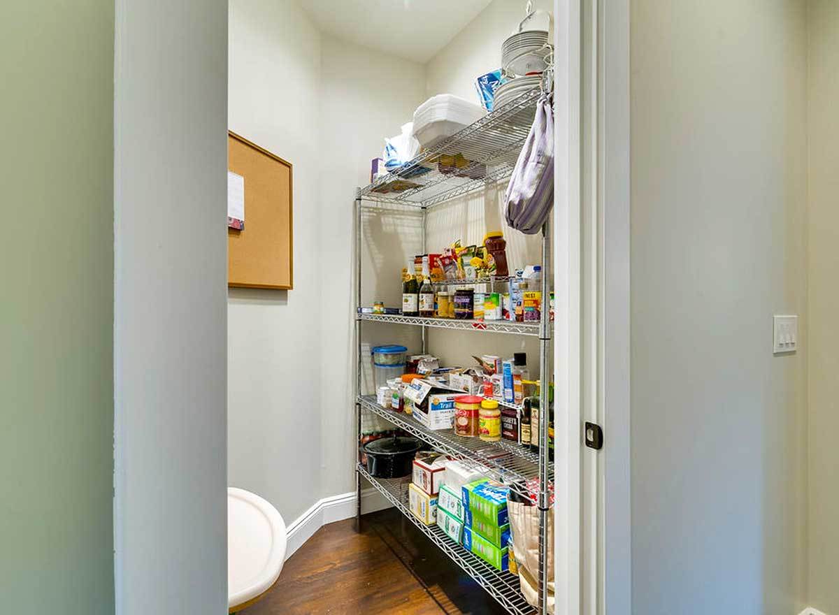 一个带金属架子的步入式食品储藏室，里面装满了食品杂货。
