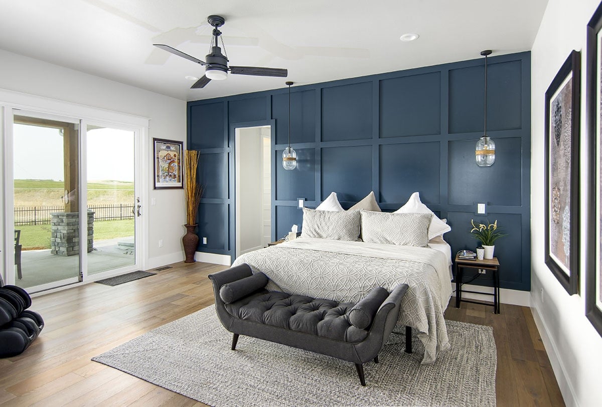 主卧室有一个令人惊叹的蓝色镶板强调墙，一个簇绒长椅与床互补，并有盖的门廊入口。