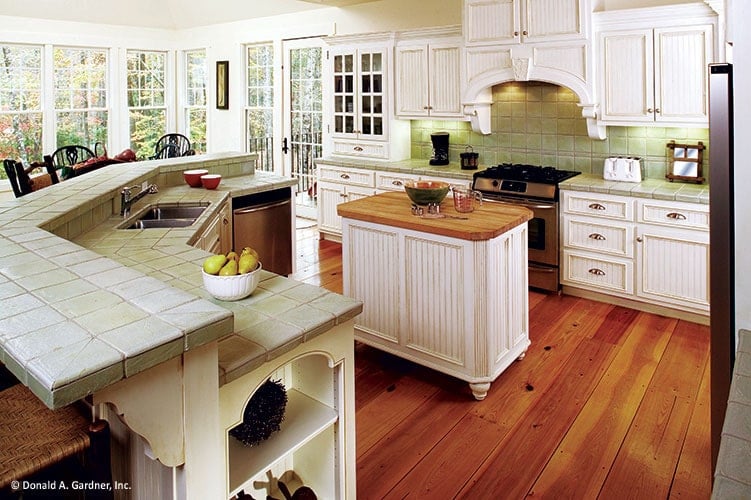 厨房里有床头板橱柜，一个中央岛，一个带有双碗水槽的弧形用餐吧台。