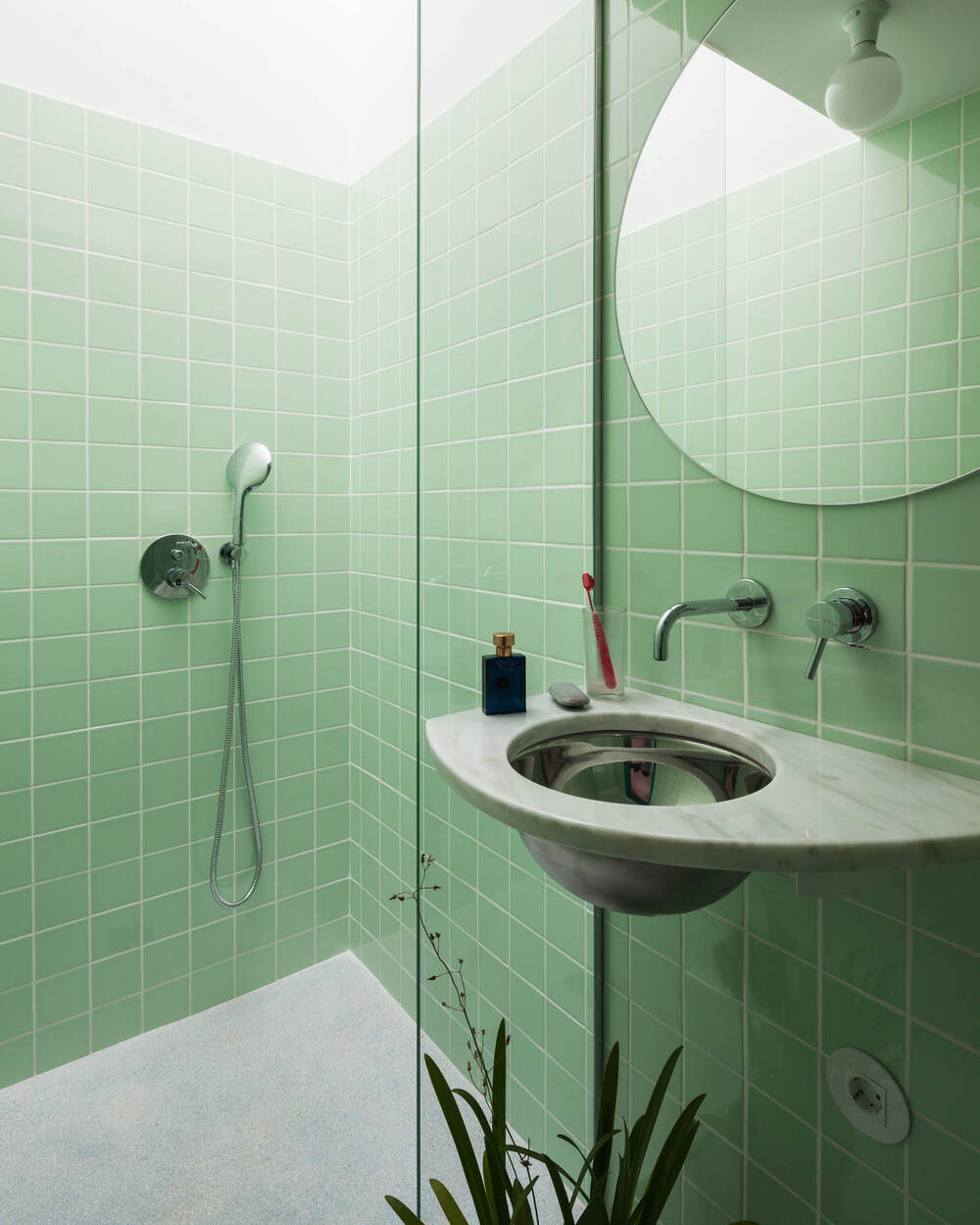 浴室墙壁上贴着一致的绿色瓷砖，使固定装置脱颖而出。