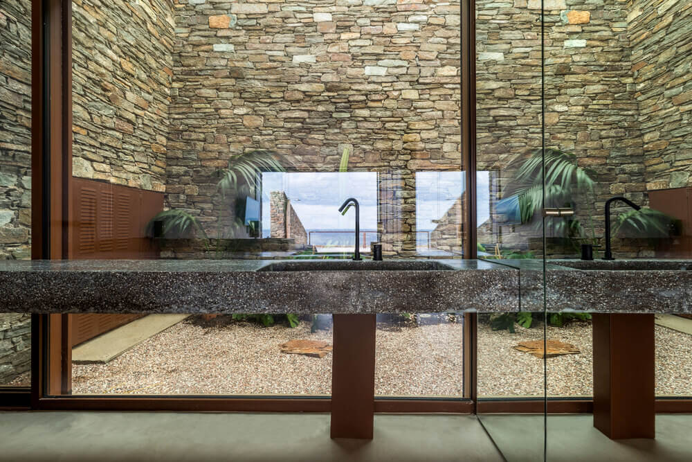 在浴室的玻璃墙后面，是一个有土坯砖墙的微型花园。
