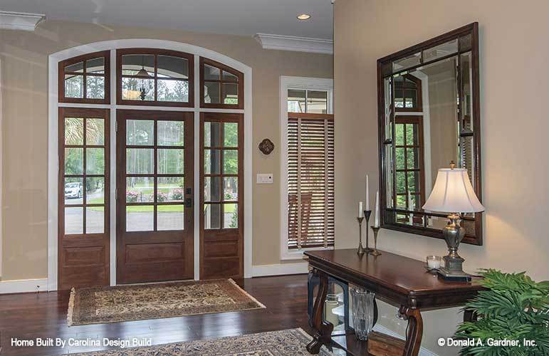 门厅里有一扇玻璃框的入口门和一个木制控制台，配有一面装饰性的镜子。